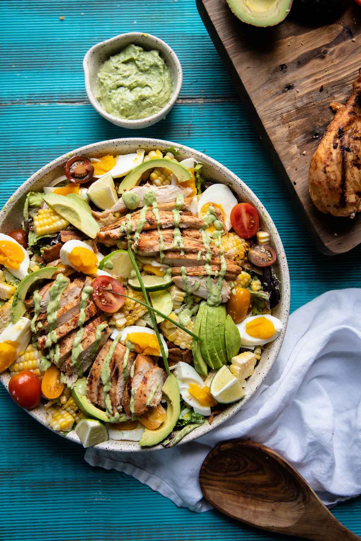 overhead image of cobb salad topped with grilled chicken and greed goddess drizzle