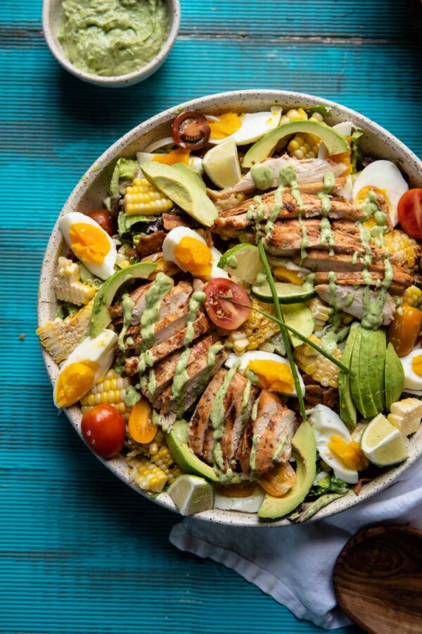 overhead image of cobb salad topped with grilled chicken and greed goddess drizzle