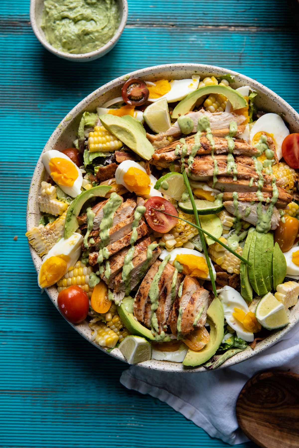 overhead image of cobb salad topped with grilled chicken and greed goddess drizzle