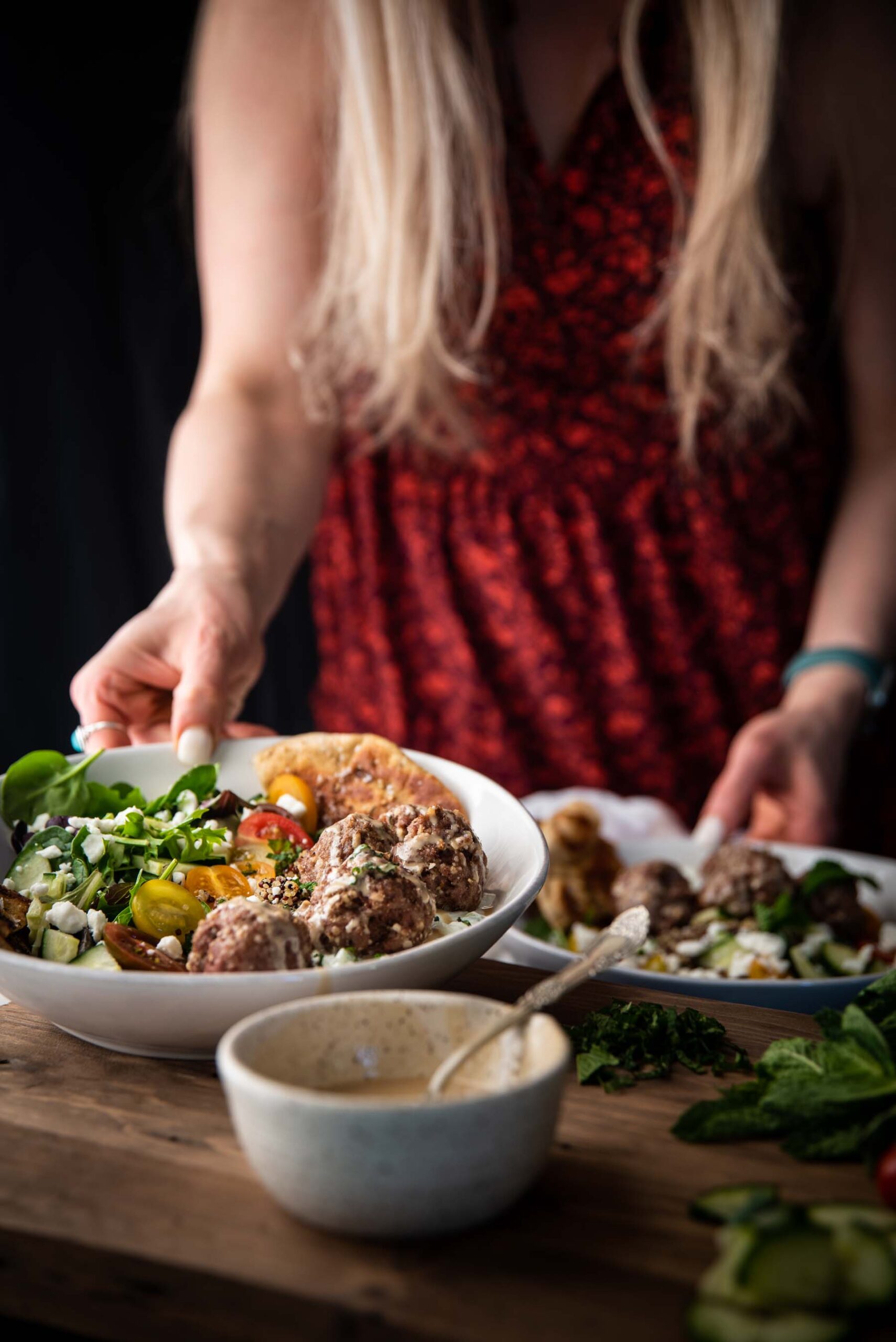 hands grabbing bowls with mediterranean quinoa bowl ingredients