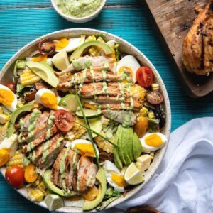 overhead image of cobb salad topped with grilled chicken and greed goddess drizzle