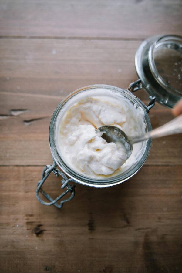 overhead of garlic aioli in a glass jar with a spoon