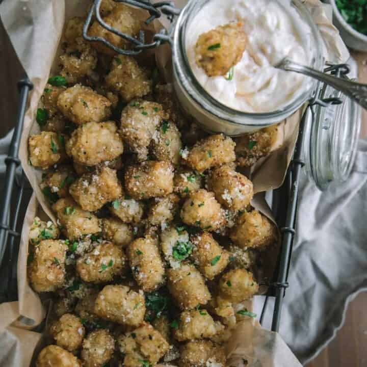 overhead of tater tots in parchment lined basket with garlic aioli