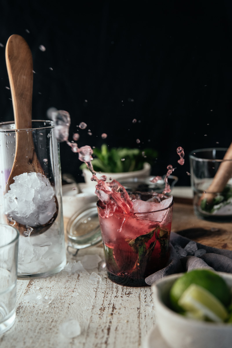 ice cube thrown into glass splashing cocktail all over