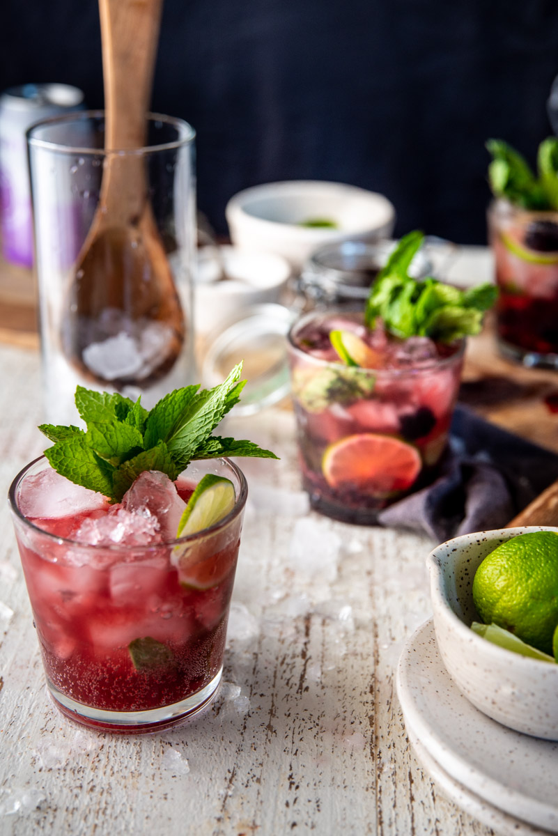 side angle of blackberry mojitos in glasses with mint garnishes