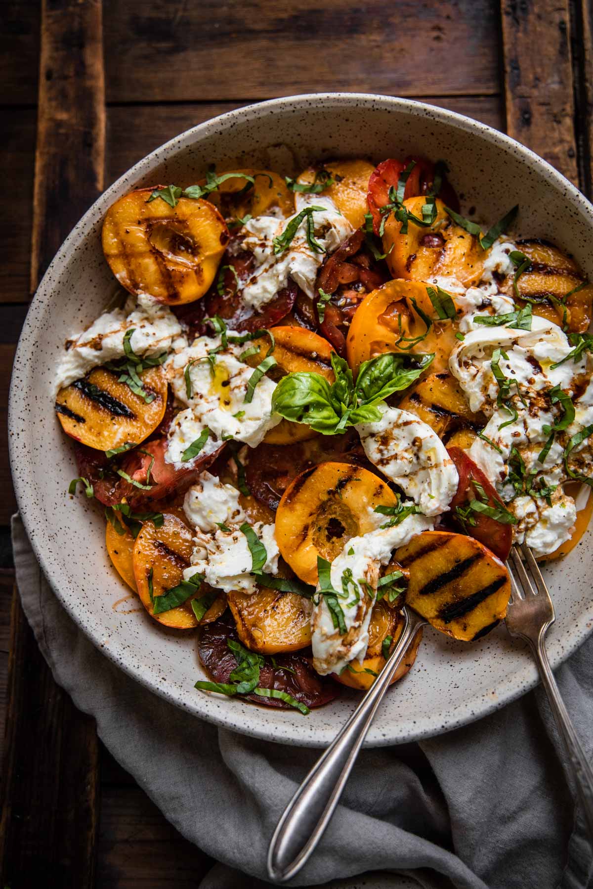 grilled peaches, sliced tomatoes and burrata in a platter bowl