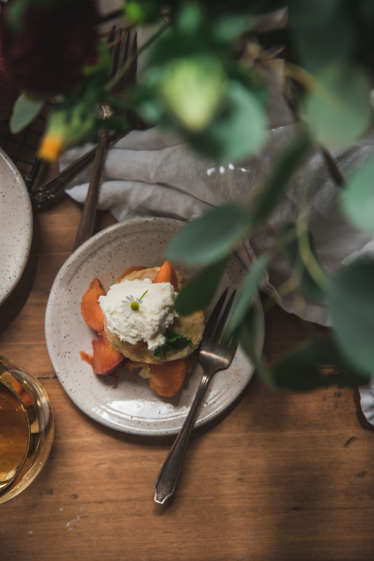 overhead of peaches stacked on biscuits with whipped cream