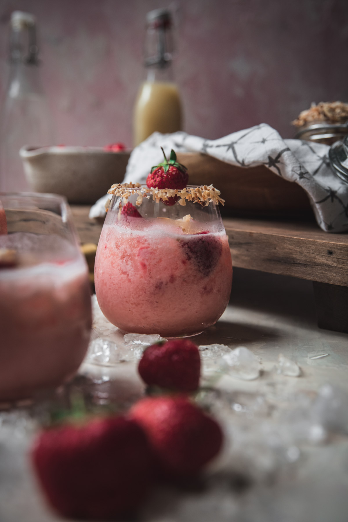 strawberry coconut margarita in a glass with coconut rim and strawberry garnish