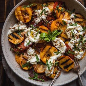 grilled peaches, sliced tomatoes and burrata in a platter bowl