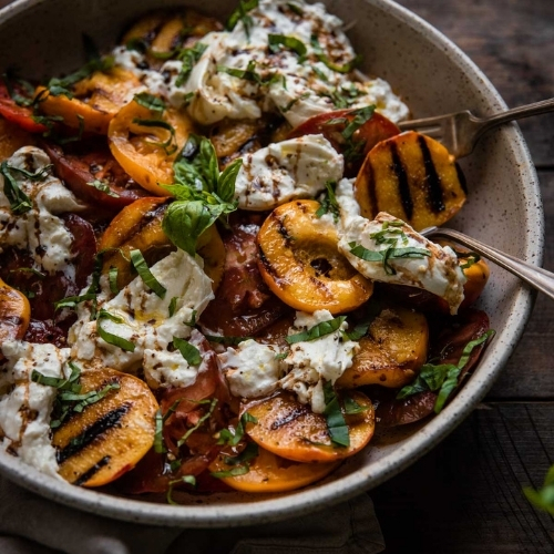 grilled peaches, sliced tomatoes and burrata in a platter bowl