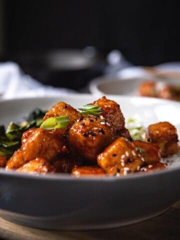 side angle of fried tofu in a bowl with spicy korean sauce