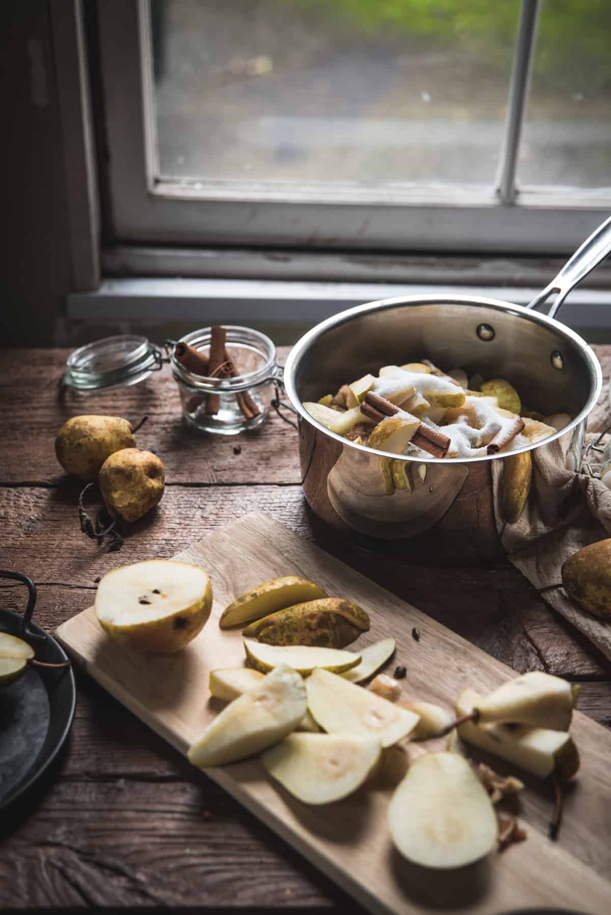 side angle of pan full of sugar, pears, and cinnamon sticks