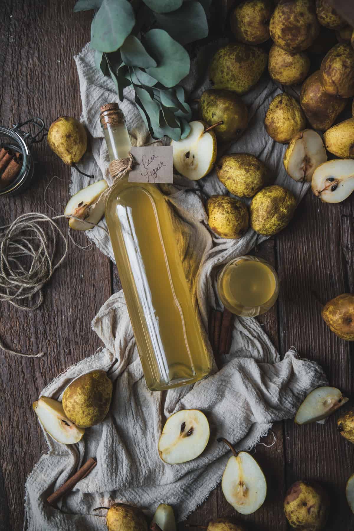 overhead of fruit infused liquor in a bottle surrounded by pears