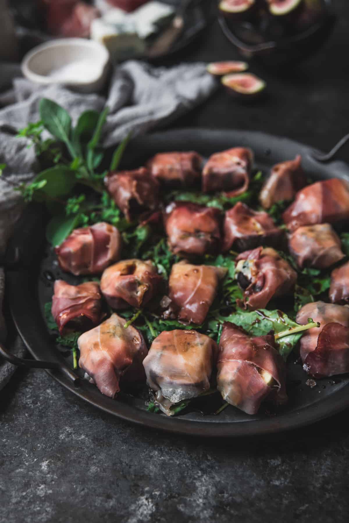 baked figs with prosciutto and blue cheese on a silver tray