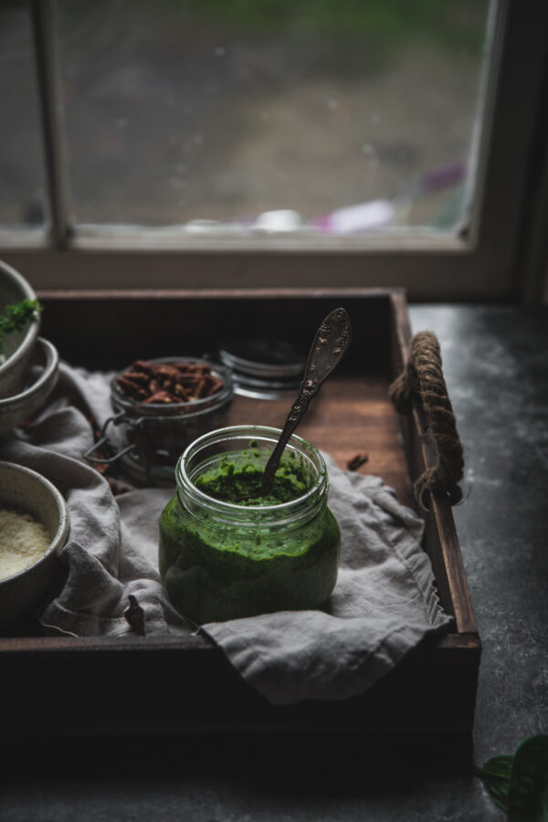 pesto in a jar on a tray in front of a window