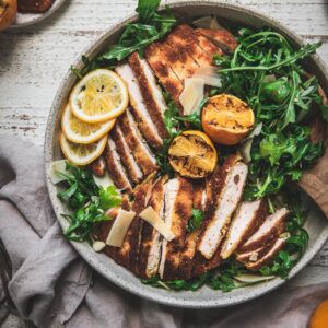 sliced crispy chicken over arugula with grilled lemon