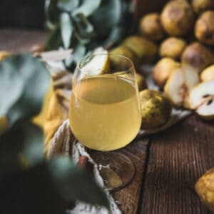 pear cordial in a glass surrounded by pears