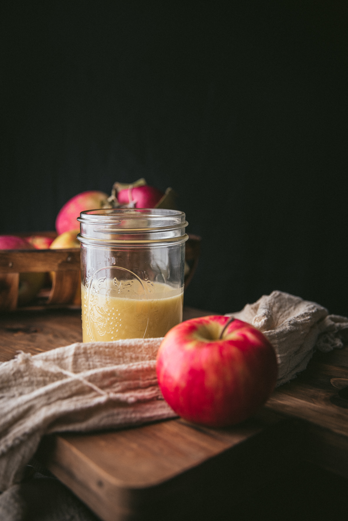 dressing in a mason jar with a red apple in front of the jar