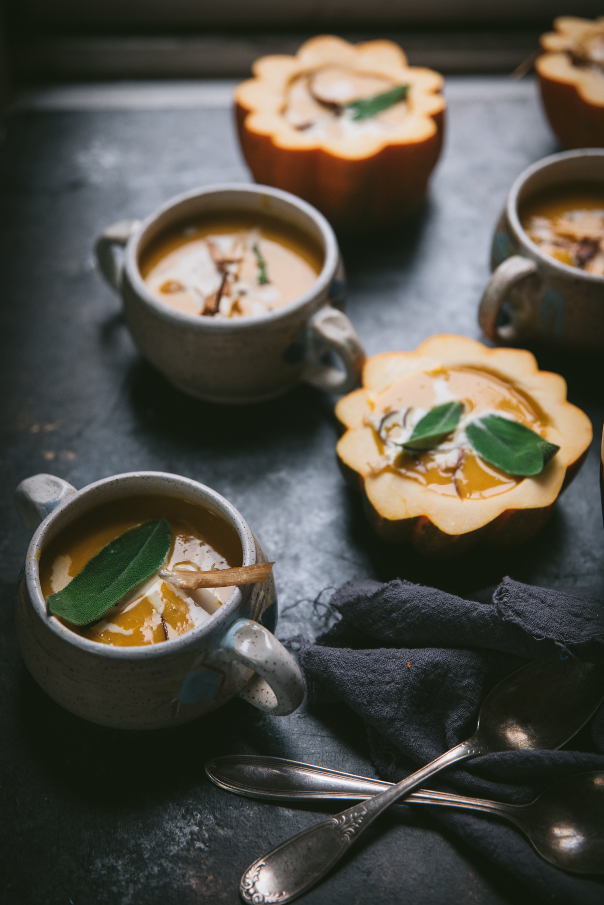 backlit bowls of soup with sage on top