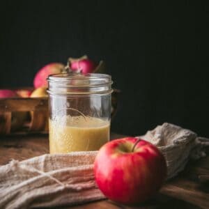 apple cider vinaigrette dressing in a mason jar with linen napkin and bright red apple