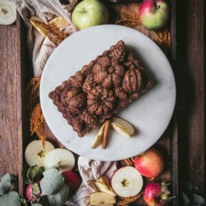 overhead of fall themed apple moaf on a cake stand surrounded my apples