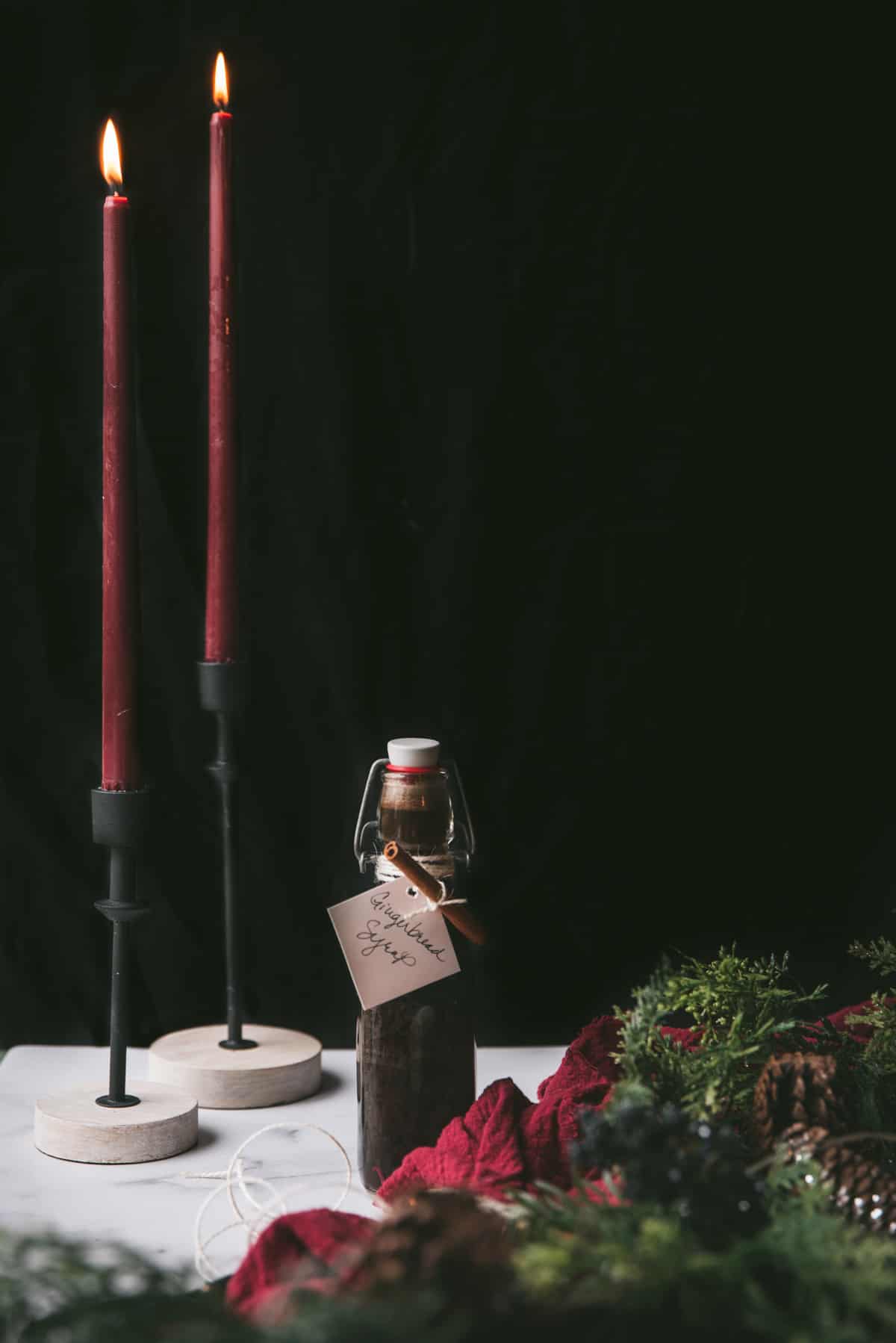 gingerbread syrup in flip top bottle with candle sticks and christmas wreath