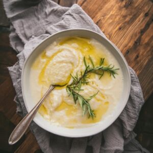 overhead photo of pureed parsnips in a bowl with a spoon and oil drizzle