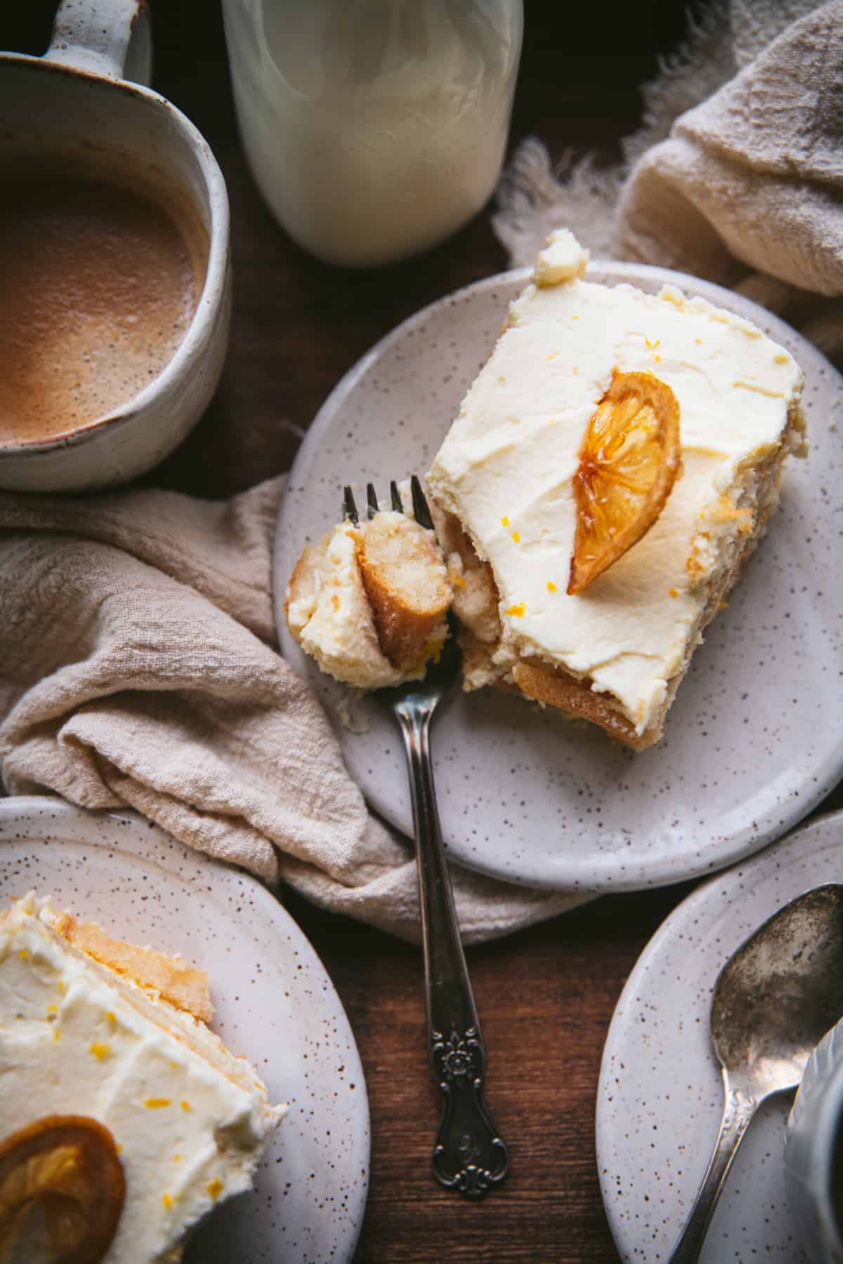 overhead of slice of tiramisu on a plate with a fork taking a bite of the piece