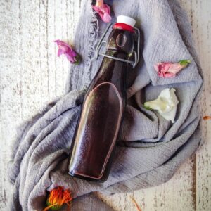 hibiscus syrup in a bottle with fresh flowers on linen