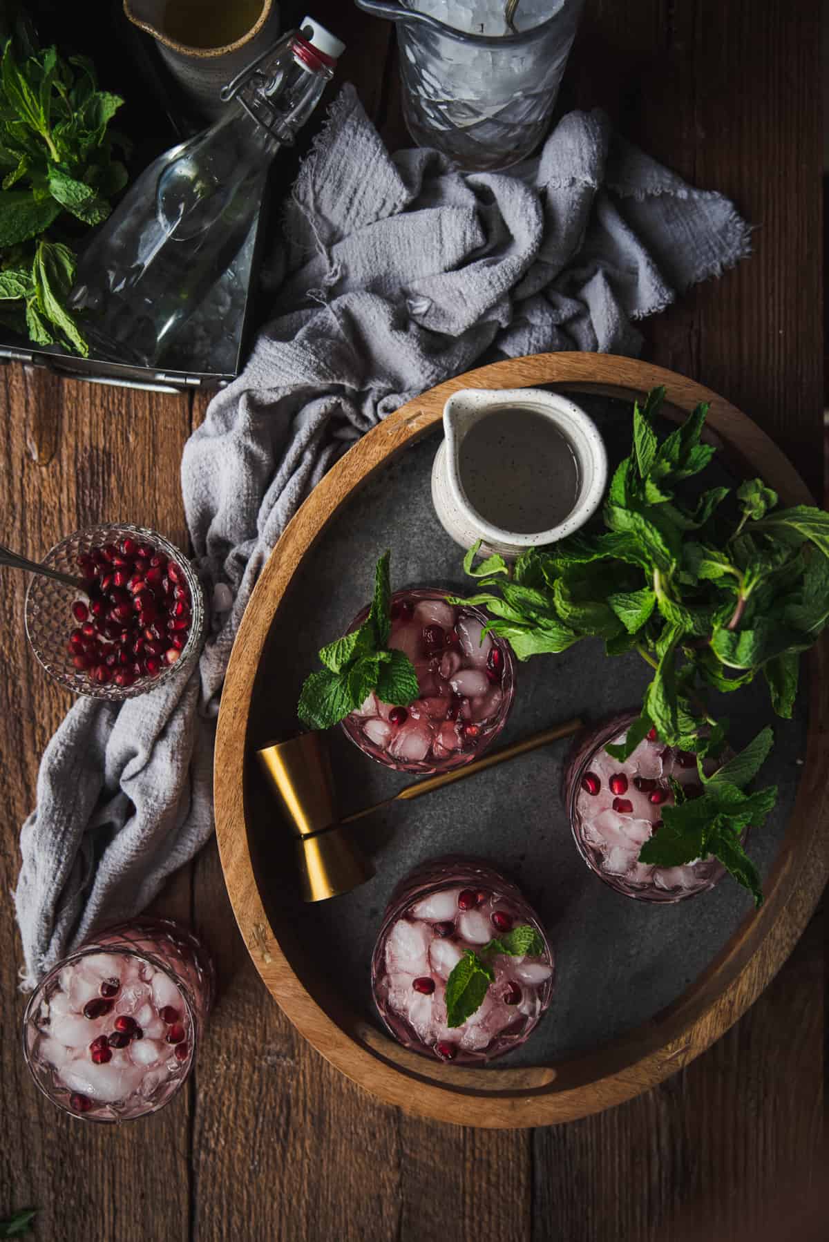 overhead photo of pomegranate cocktails on a drink tray surrounded by ingredients