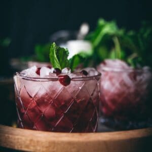 side angle close up on pomegranate mojito topped with somegranate seeds and fresh mint