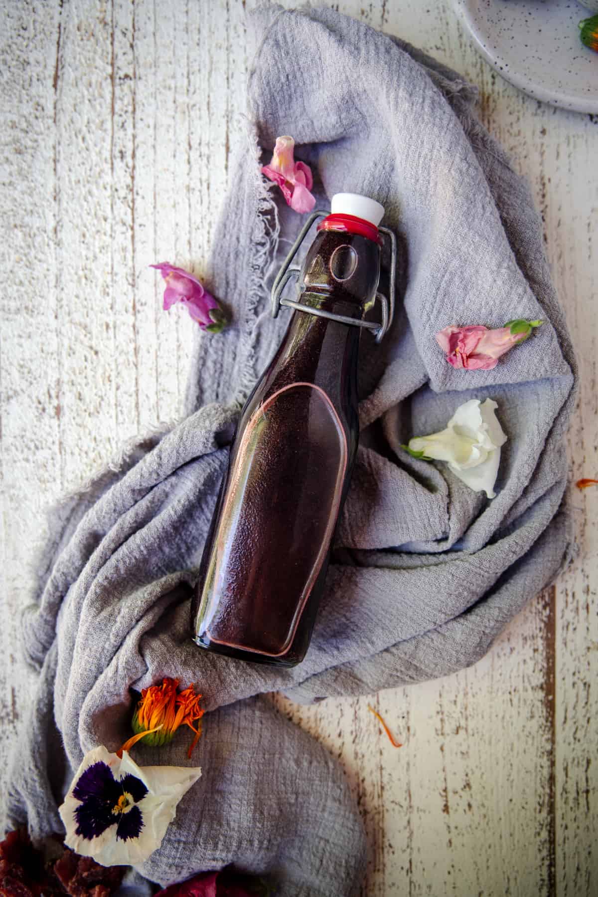 hibiscus syrup in a bottle with fresh flowers on linen