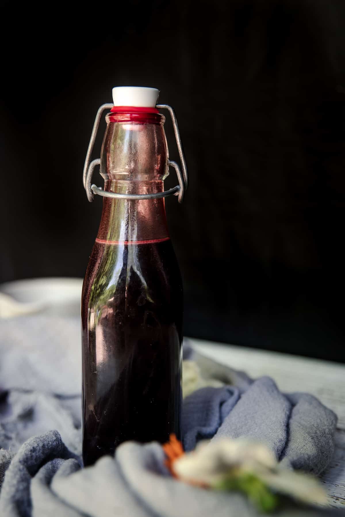 dark red syrup in a pop top bottle with black background