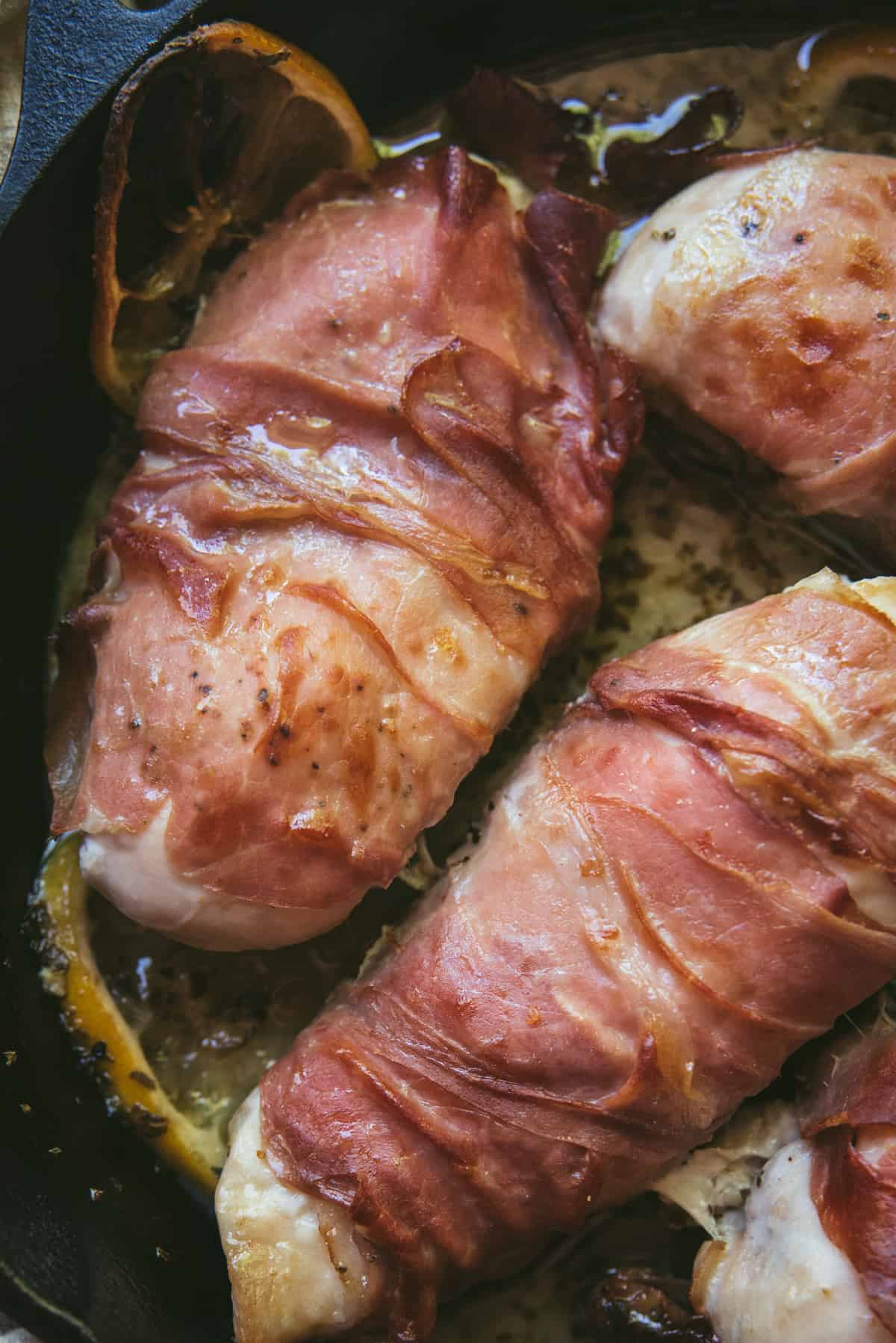 close up of baked chicken wrapped with prosciutto