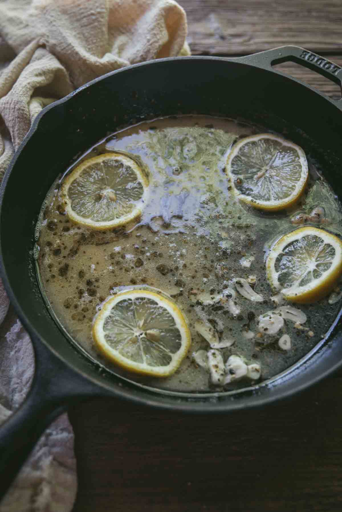pan sauce with lemon slices in a cast iron pan