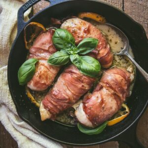 prosciutto wrapped chicken in a cast iron skillet with wine sauce