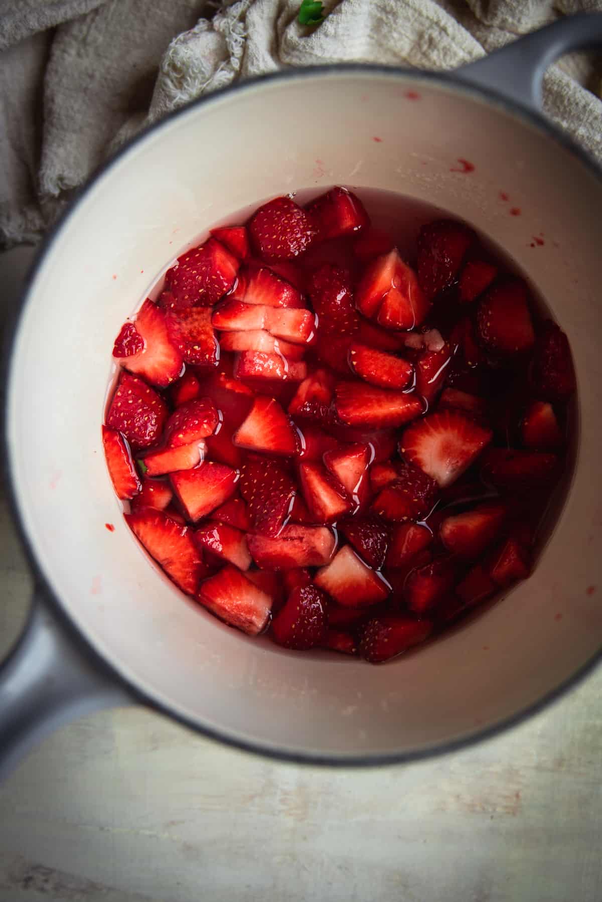 overhead image of sliced strawberries in simple syrup in a sauce pan