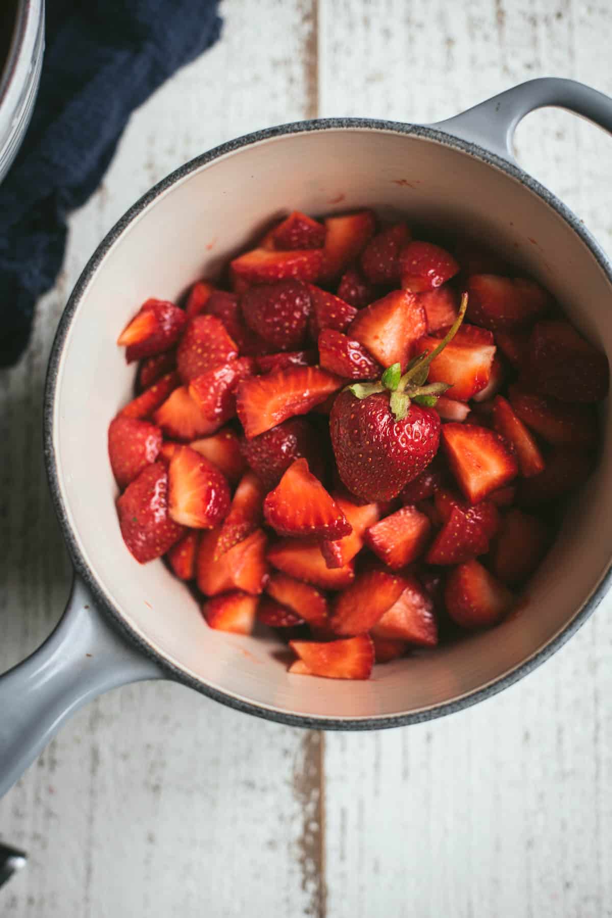 sliced strawberries in a saucepan topped with one whole strawberry