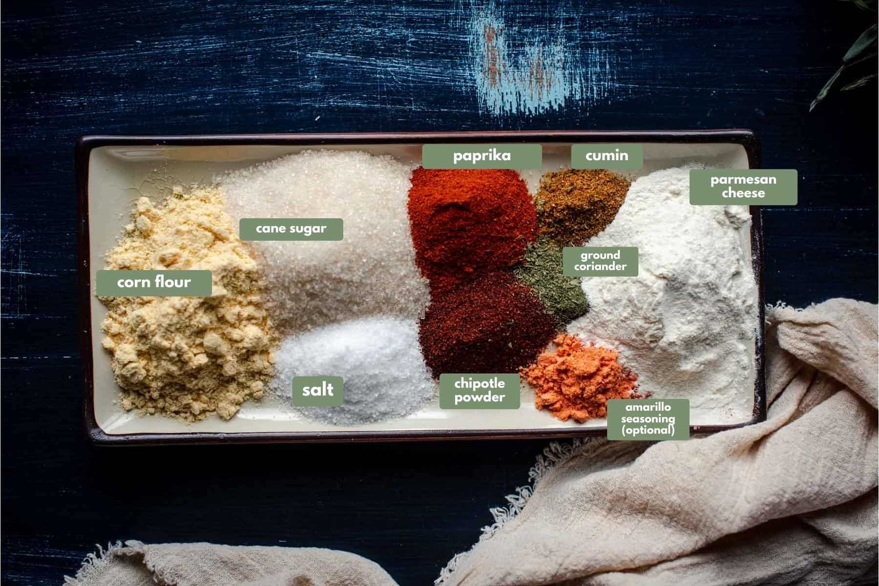 spices on a rectangular plate placed one next to the other.  Plate is on a blue background with a cream colored linen napkin.