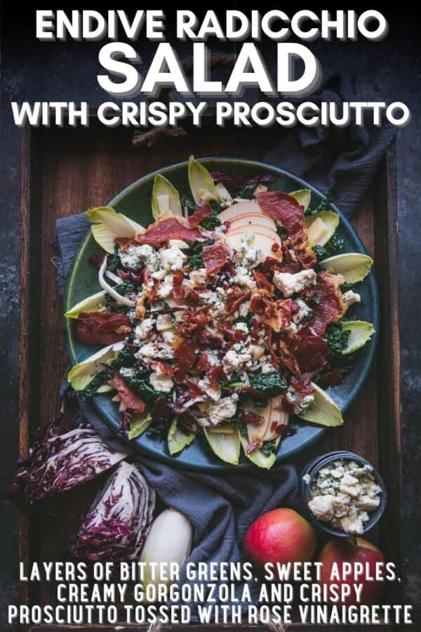 Pinterest image with text overlay of recipe name and ingredients. overhead image of salad on a large platter surrounded by whole ingredients. On the platter there is sliced kale, apples, crispy pieces of prosciutto and crumbled blue cheese on top surrounded by leaves of endive fanned along the outside of the plate.