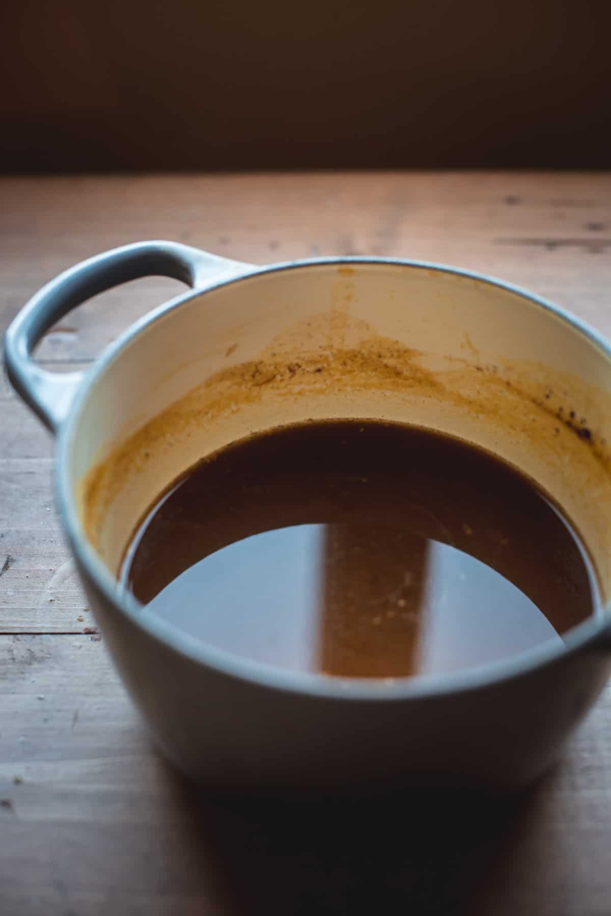 Homemade Pumpkin Spice syrup is in a large white pot having just been made.