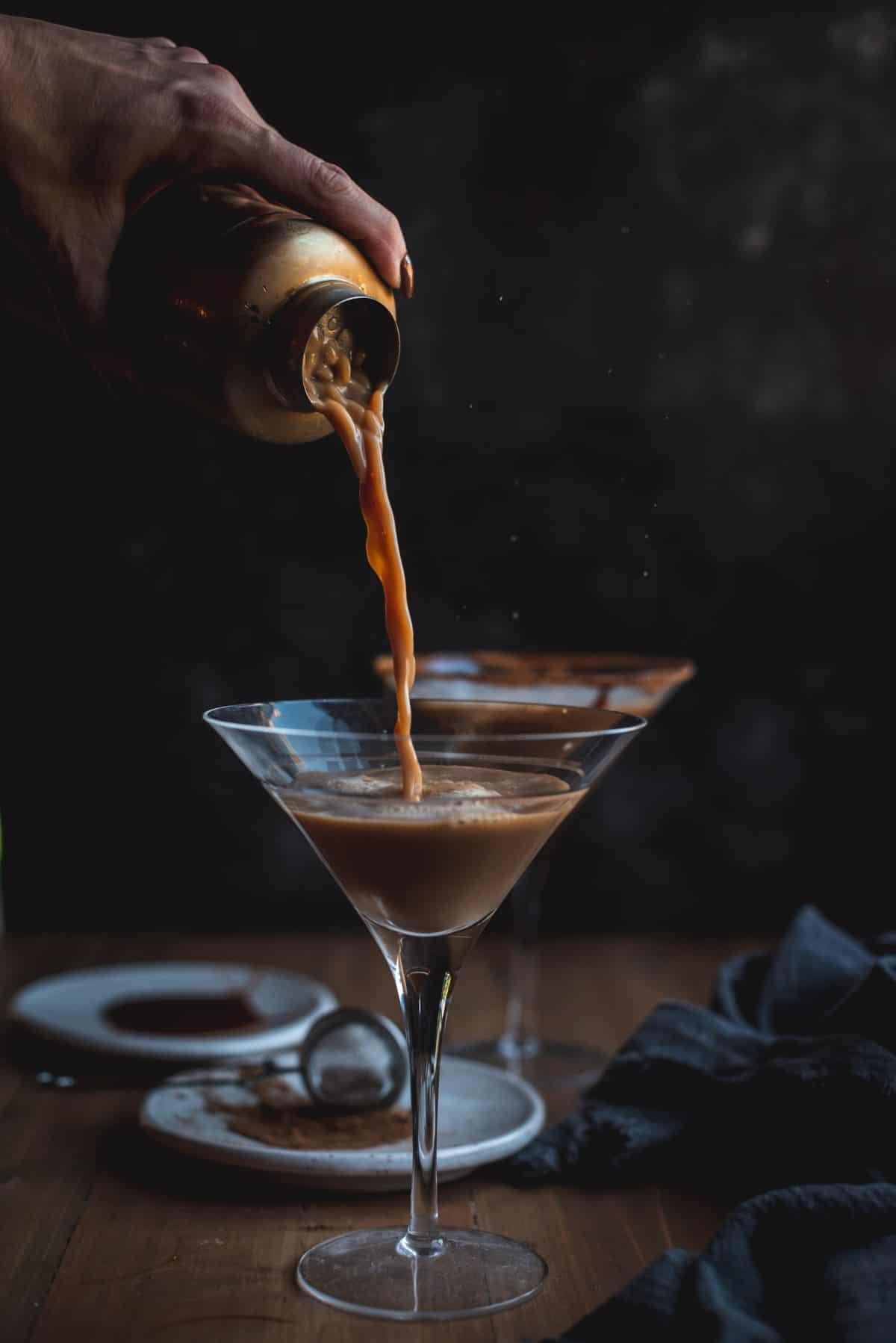 The Pumpkin Spice Latte Martini is being poured from the cocktail shaker into a clean martini glass.