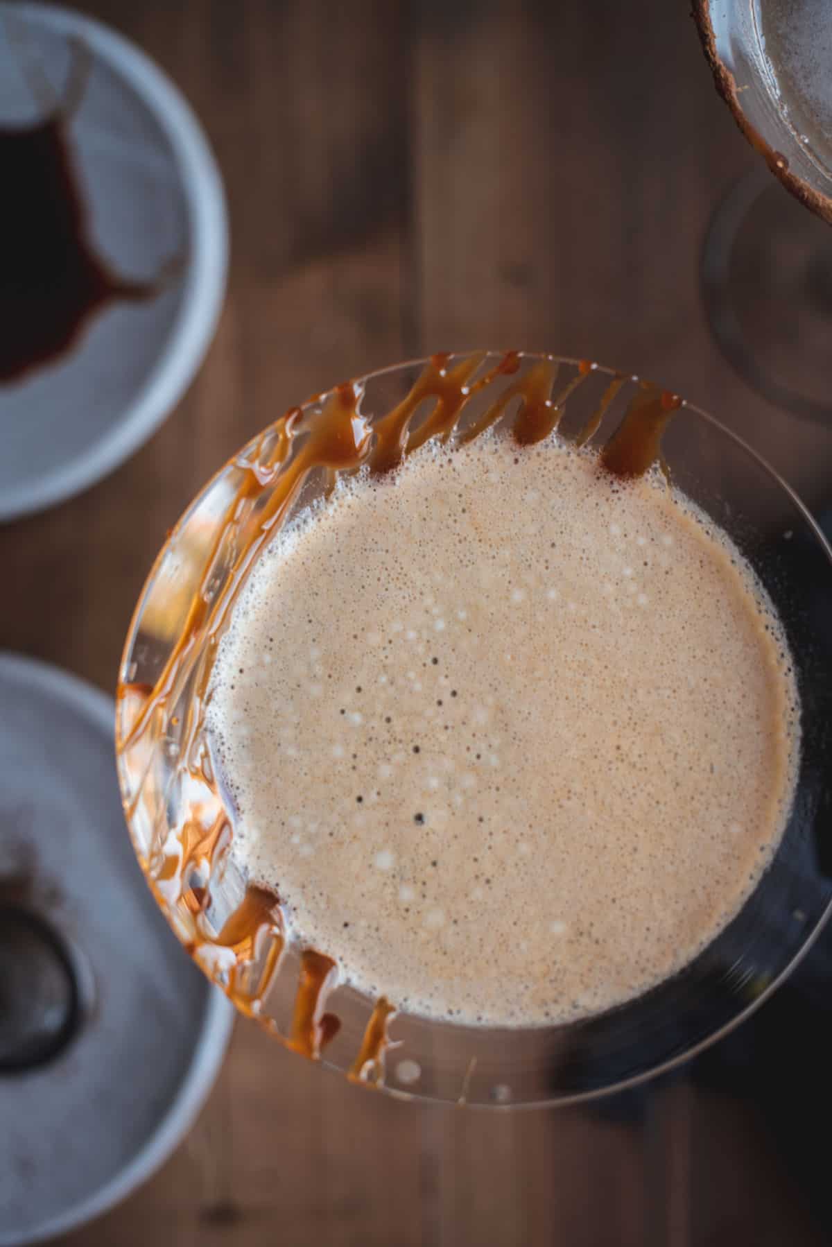 View from above of this Fall cocktail. The top is frothy with a caramel drizzle on the left side of the glass.