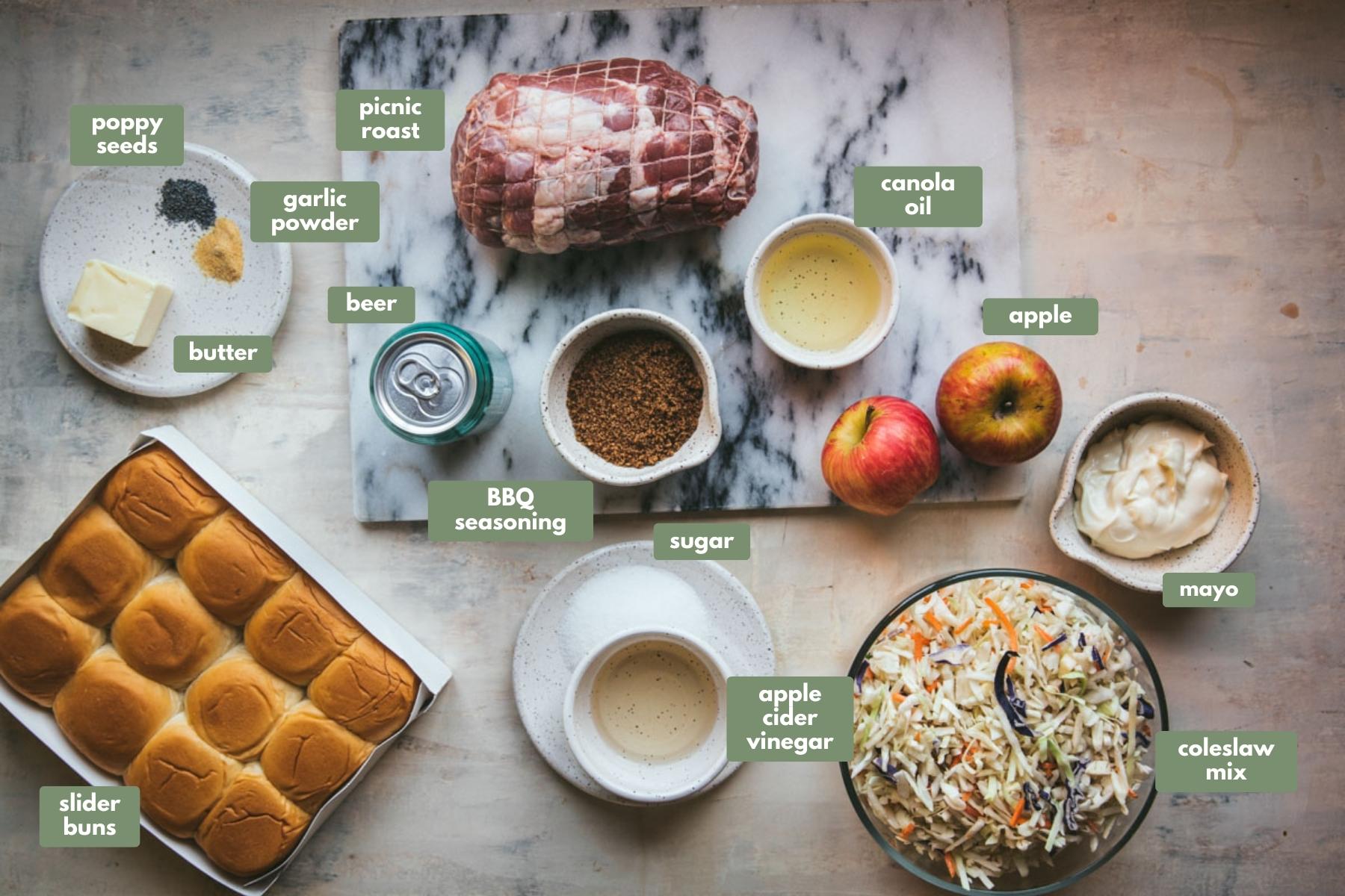 The ingredients used inside of this pulled pork slider recipe. There is a pork picnic roast  tied up in string sitting on a white marble chopping board. Also on the board is a can of beer, a bowl of bbq seasoning, 2 apples and a small bowl with canola oil. Next to the board the is a small bowl with mayo inside and next to that is a large bowl of coleslaw mix. These is also a white plate with sugar and a small bowl of apple cider vinegar is sitting on top too. There is a white box containing 12 slider buns and a plate with butter, poppy seeds and garlic powder.