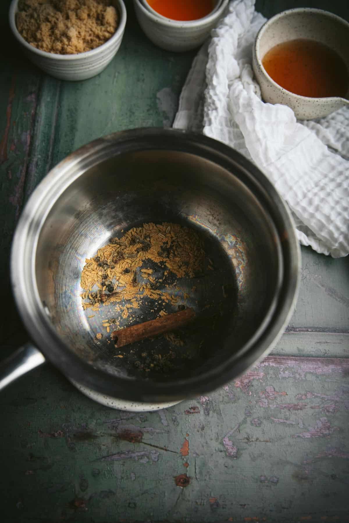 A silver bowl is sitting with the spices in the botto of it.