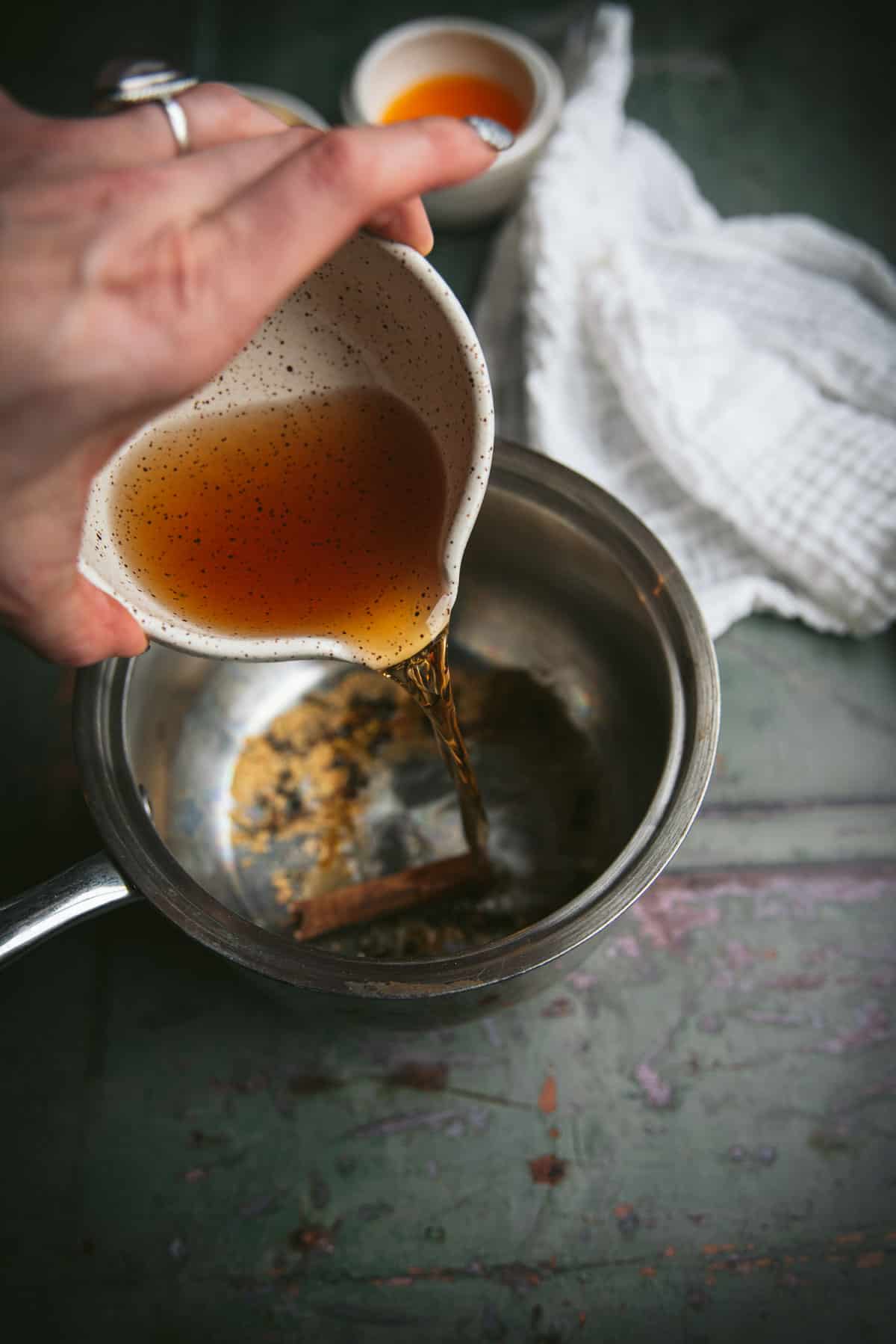 Someone is pouring the bourbon into the silver bowl with spices.